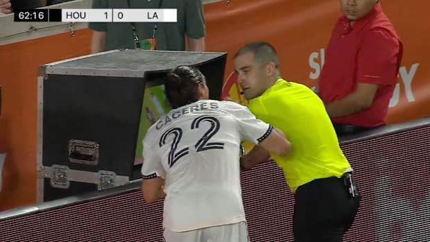 Martín Cáceres tocando a réferi mientras analiza el VAR